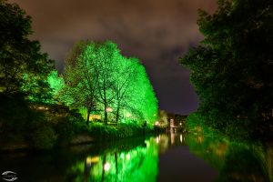 View over river Pegnitz with green illuminated trees at the city beach.