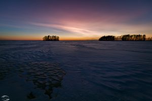 Twilight over a frozen lake with some islands in the background