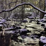 Snow covered stones in rapids at night