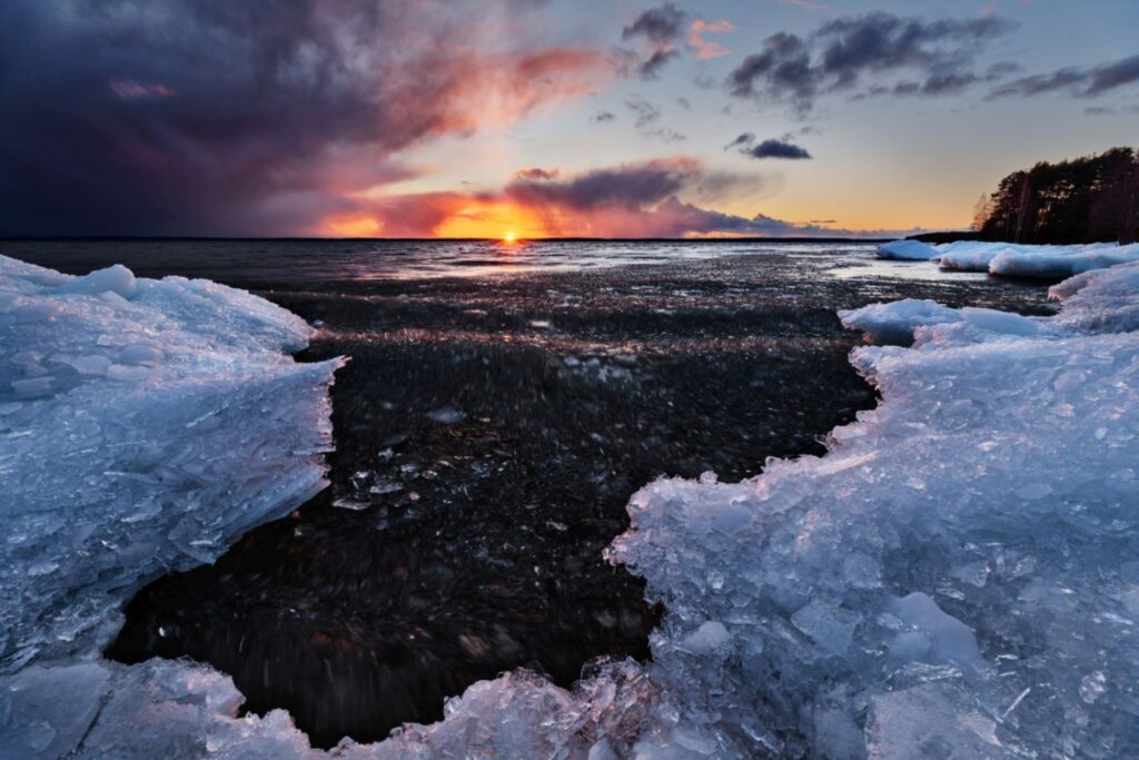 Eisiges Ufer bei Sonnenuntergang: Eisschollen glänzen im warmen Licht des Abendhimmels.