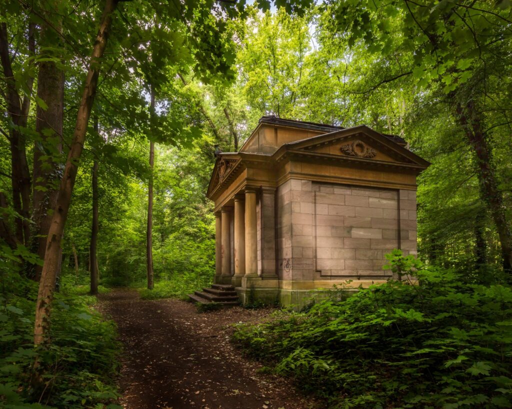 Neoklassizistischer Waldpavillon mit Säulen im Grünen – historischer Gartenbau im Wald.