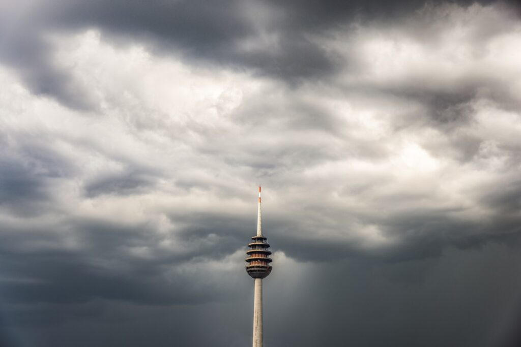 Fernsehturm vor dunklem Wolkenhimmel, ikonischer Aussichtsturm in Berlin.