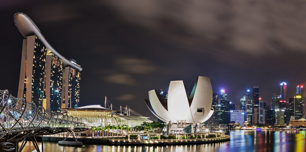 Nachtaufnahme der Skyline von Singapur: Marina Bay Sands, ArtScience Museum und Helix-Brücke am Marina Bay.