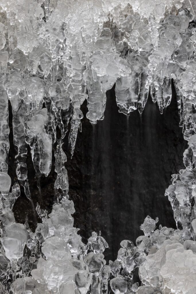 Eiszapfen und Eisformationen in einer dunklen Eishöhle – beeindruckende Naturfotografie
